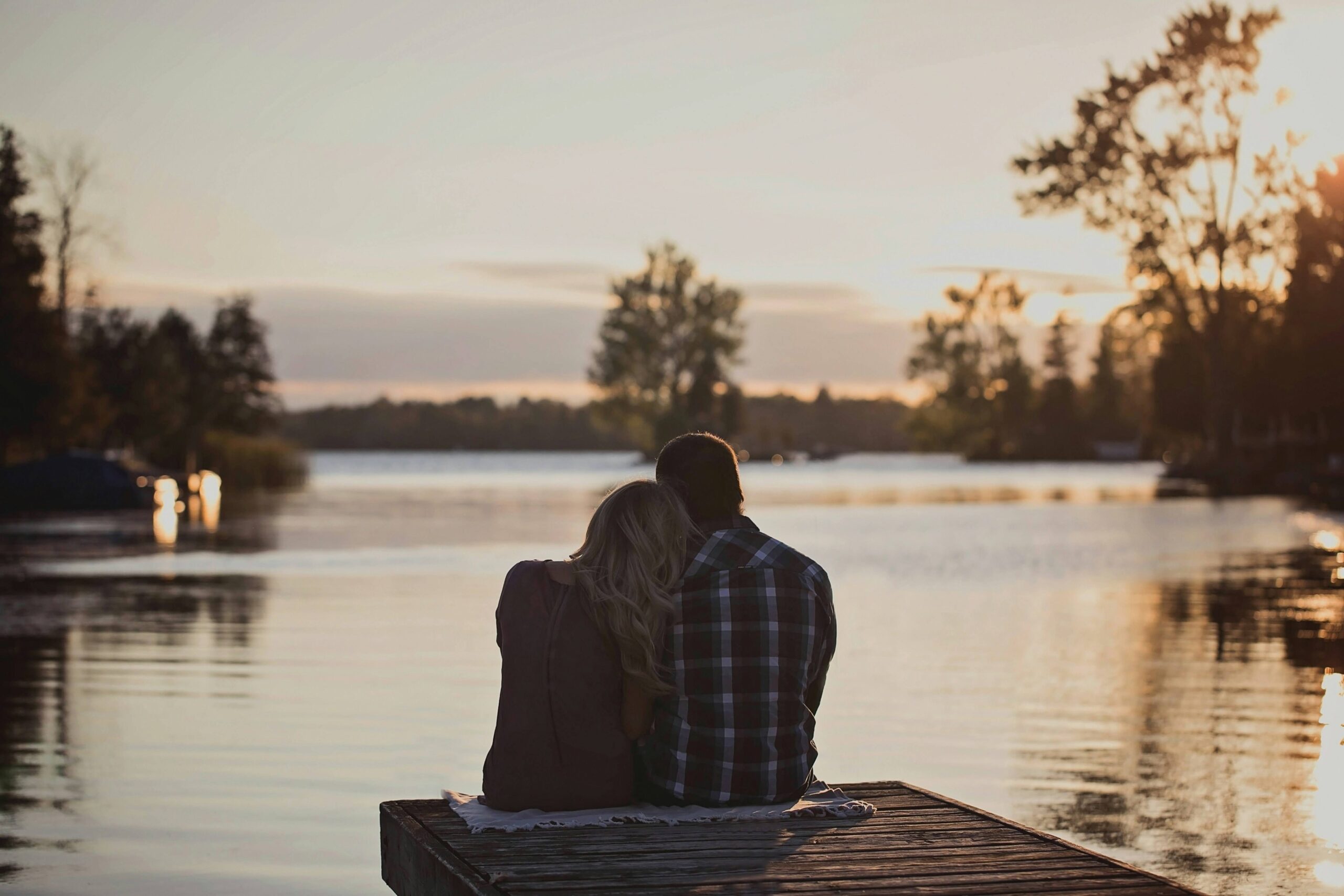 Couple sitting together on a dock at sunset after couples counselling in Vancouver